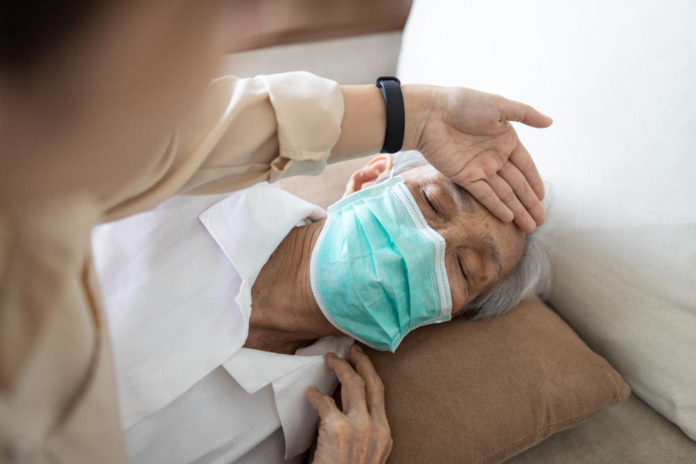 Asian man with flu like symptoms wearing a mask.