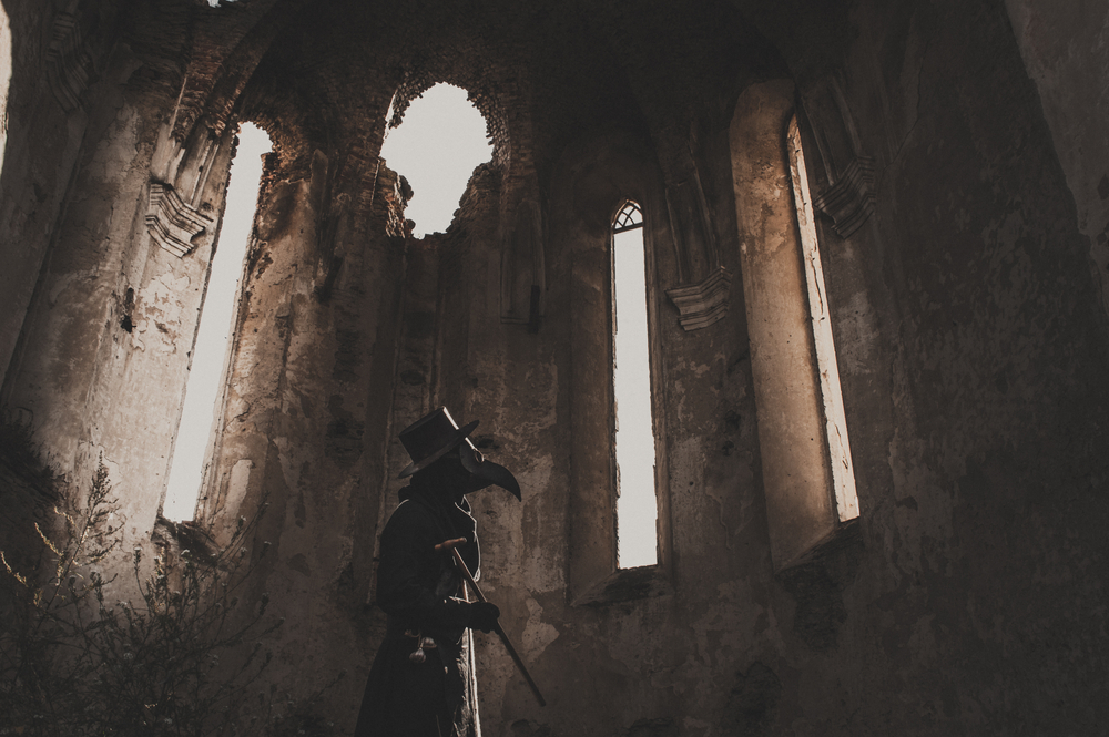 Plague doctor in ruined building.